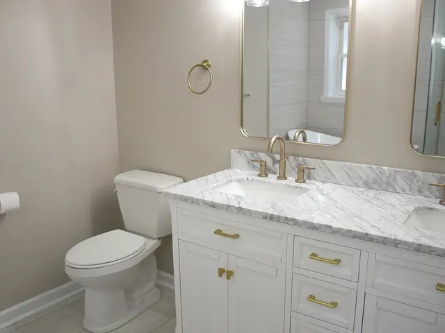 a bathroom with a granite countertop toilet sink and mirror