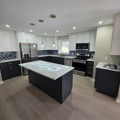 a large kitchen with stainless steel appliances kitchen island granite countertop a stove a sink a refrigerator and a microwave