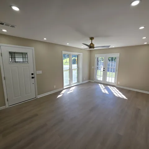 an empty room with windows and chandelier fan