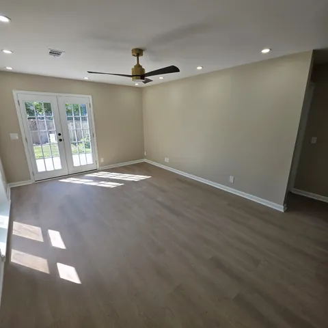 an empty room with wooden floor fan and windows