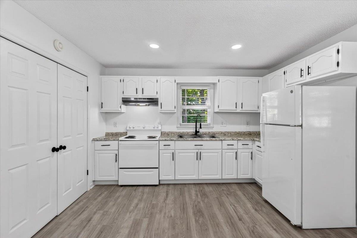 2717 Merle Street Memphis, TN 38118 - Photo 2 of 18 Bright kitchen featuring white cabinetry with dark hardware, a white range, a white refrigerator, light-toned countertops, and wood-finish flooring