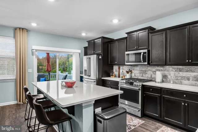 a kitchen with stainless steel appliances granite countertop a stove a refrigerator a sink a dining table and chairs