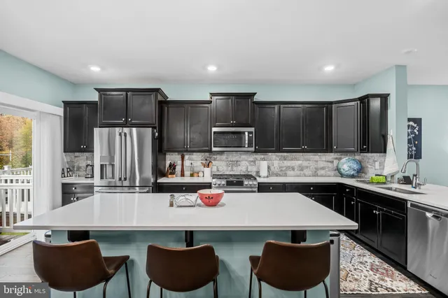 a kitchen with a stove a sink a microwave a dining table and chairs