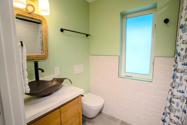 a bathroom with a granite countertop sink and a toilet