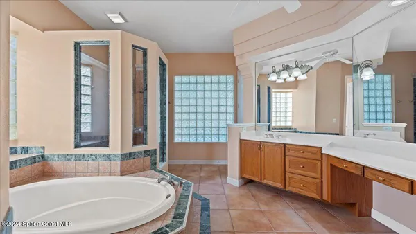 a bathroom with a tub a sink and a large mirror