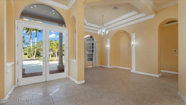 a view of a hallway with chandelier and glass door