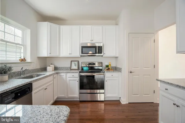 a kitchen with granite countertop white cabinets and stainless steel appliances