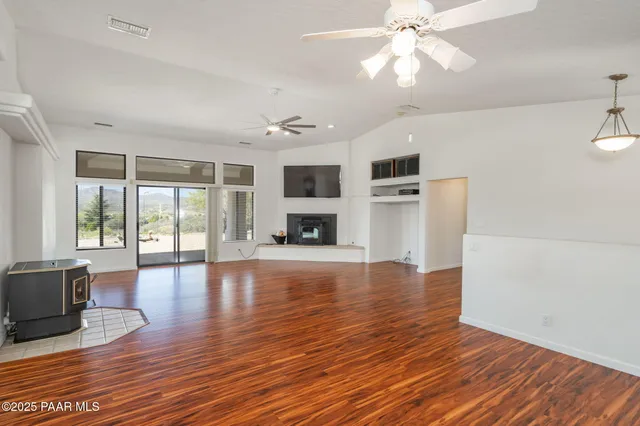 a view of an empty room with window and wooden floor