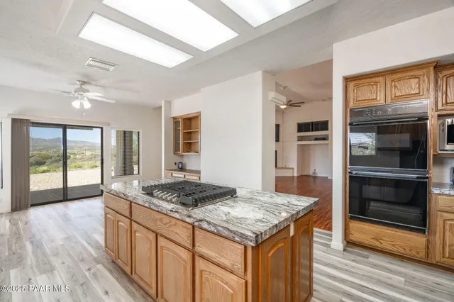 a view of a kitchen island a sink wooden floor and a large window