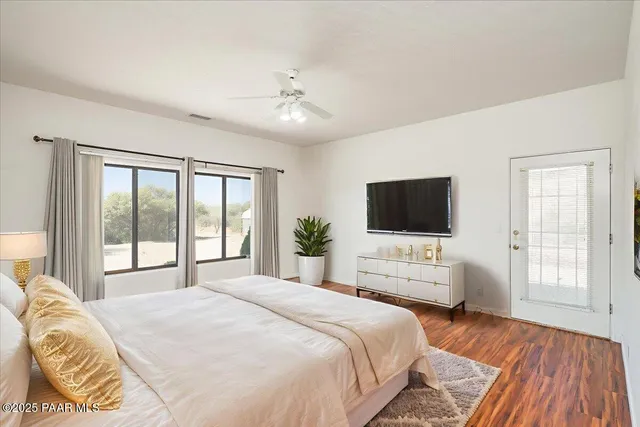 a bedroom with a bed and a large window with wooden floor