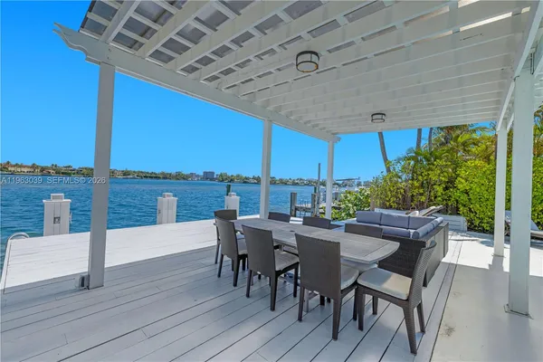a view of a roof deck with table and chairs couches with wooden floor and fence
