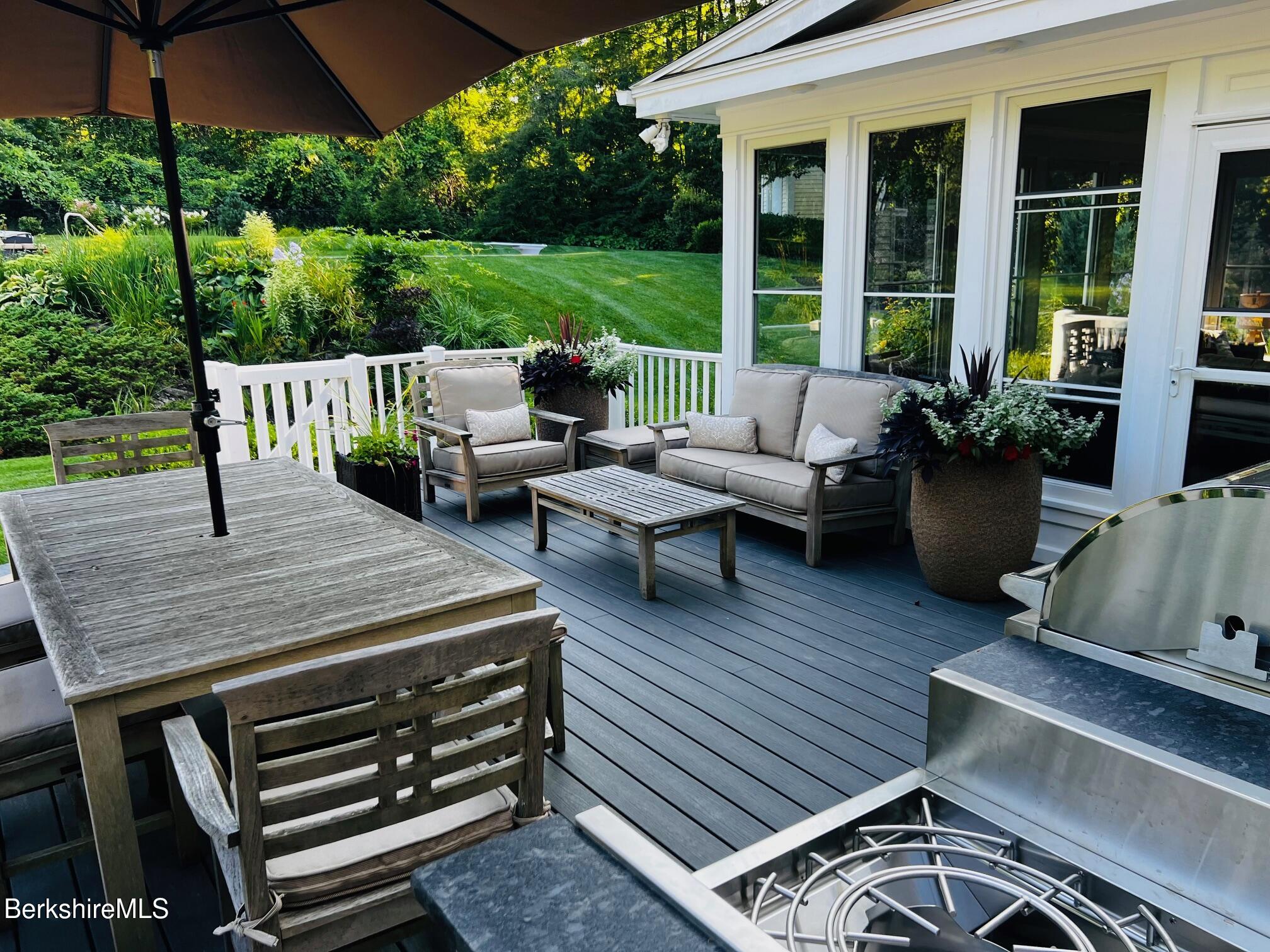 130 East Dugway Road Lenox, MA 01240 - Photo 89 of 89 a view of a patio with couches and table and chairs under an umbrella with wooden floor