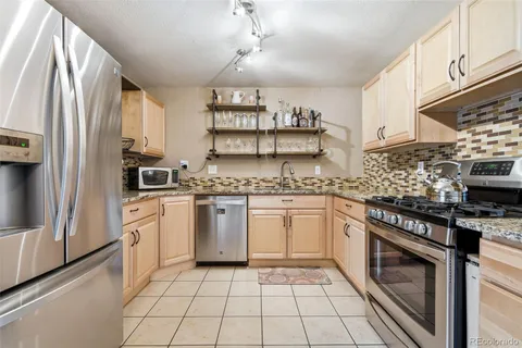 a kitchen with stainless steel appliances granite countertop a stove a sink and a refrigerator