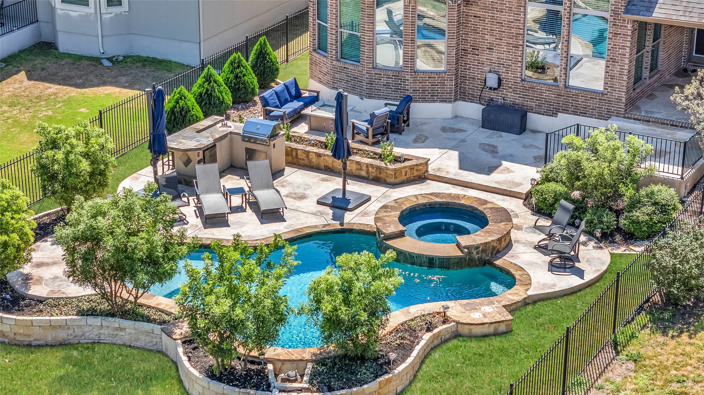 3925 Goodnight Trail Leander, TX 78641 - Photo 3 of 25 Relaxing pool / spa featuring a patio, a fenced backyard, and an outdoor kitchen with living area