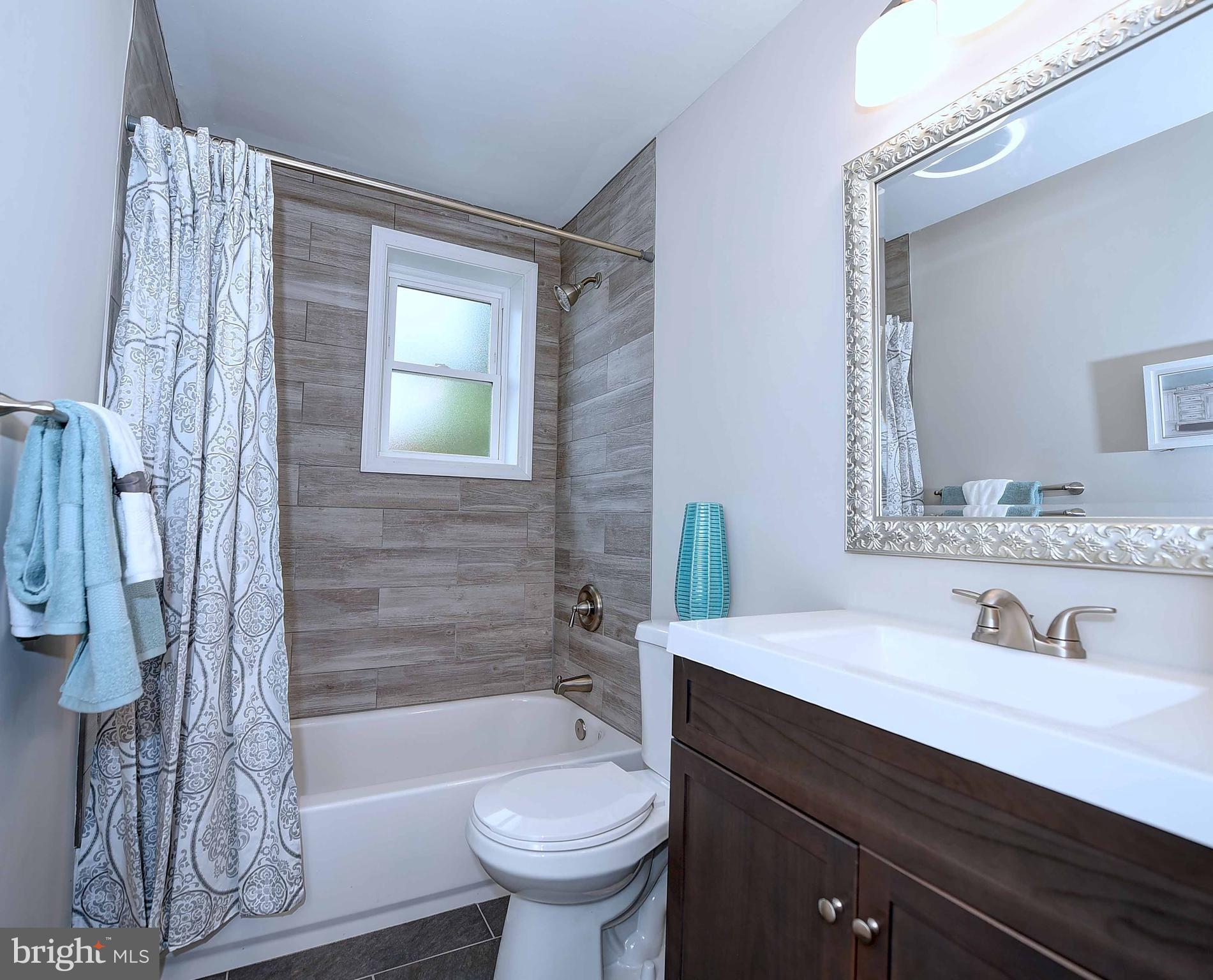 1213 Ridgeshire Road Baltimore, MD 21222 - Photo 19 of 30 a bathroom with a sink a toilet a mirror a bathtub and shower
