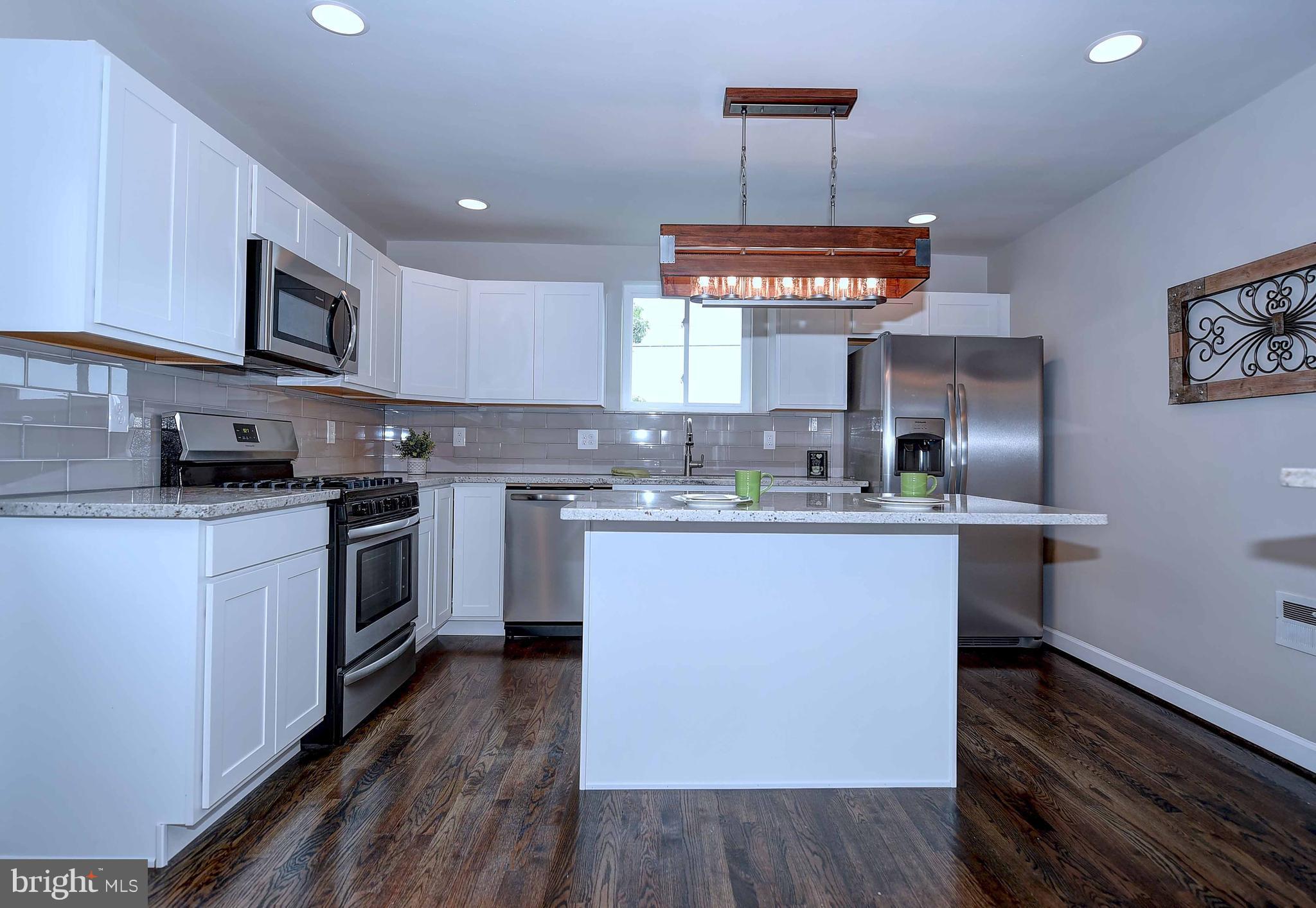 1213 Ridgeshire Road Baltimore, MD 21222 - Photo 10 of 30 a kitchen with kitchen island granite countertop a sink cabinets and wooden floor