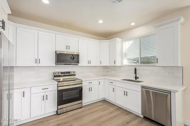 a kitchen with cabinets stainless steel appliances a sink and wooden floor