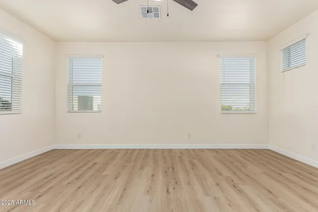 an empty room with wooden floor and windows