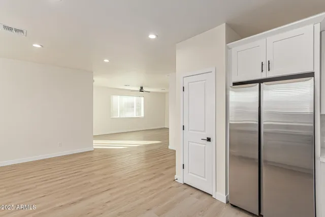 a view of an empty room with wooden floor closet and windows