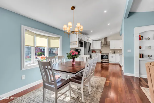 a dining room with wooden floor a chandelier a wooden table and chairs