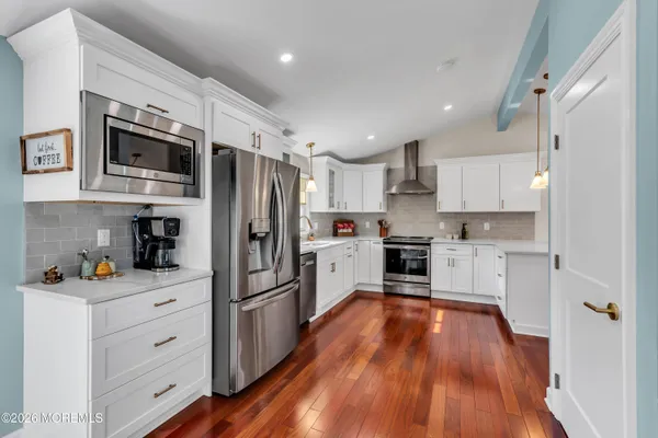 a kitchen with white cabinets stainless steel appliances and wooden floor