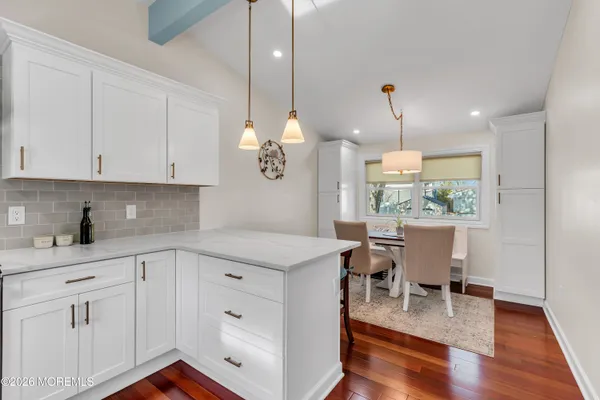 a open kitchen with white cabinets and wooden floor