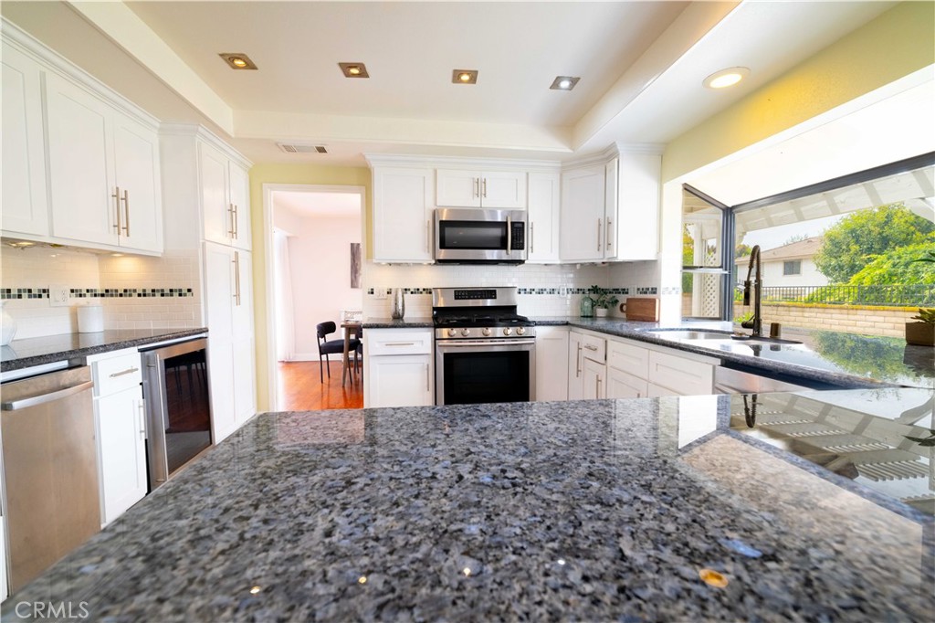 4759 Cll Estrada La Verne, CA 91750 - Photo 19 of 36 a large kitchen with stainless steel appliances granite countertop a stove top oven a sink dishwasher and a refrigerator with wooden floor