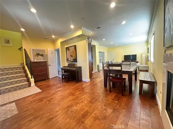 a living room with furniture a dining table wooden floor and a flat screen tv