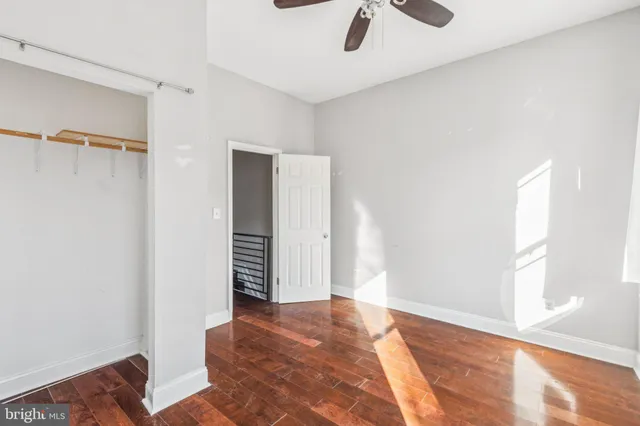 a view of a room with a ceiling fan and wooden floor