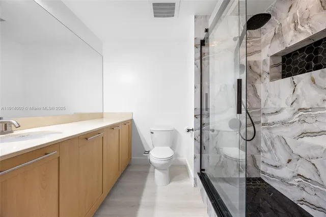 a bathroom with a granite countertop sink toilet and shower