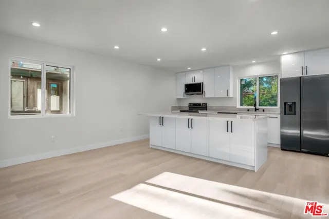 a large kitchen with stainless steel appliances a large counter top a stove a refrigerator and a sink