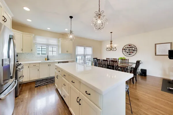 a large white kitchen with lots of counter space a sink appliances and cabinets