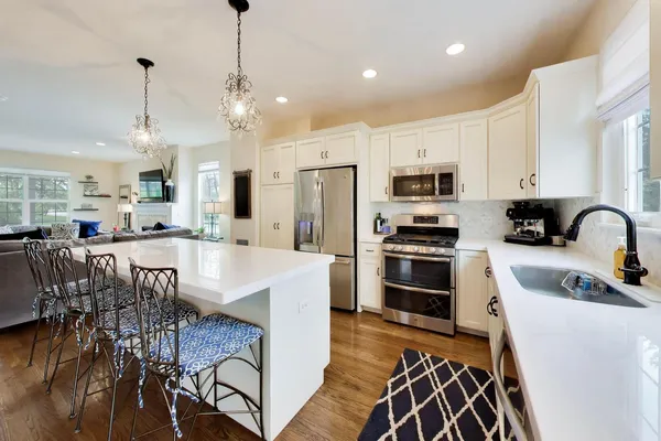 a kitchen with stainless steel appliances kitchen island granite countertop a stove a sink a refrigerator and a dining table with wooden floor