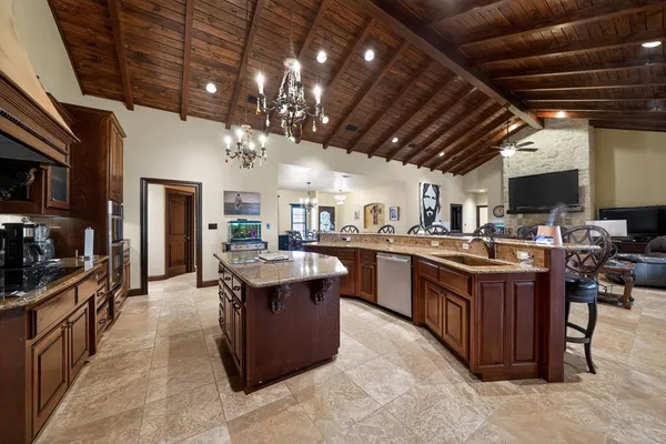 a large kitchen with stainless steel appliances granite countertop a large stove a sink dishwasher and a black countertop with chair