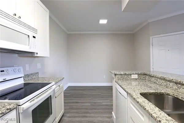 a kitchen with granite countertop a sink stove and cabinets