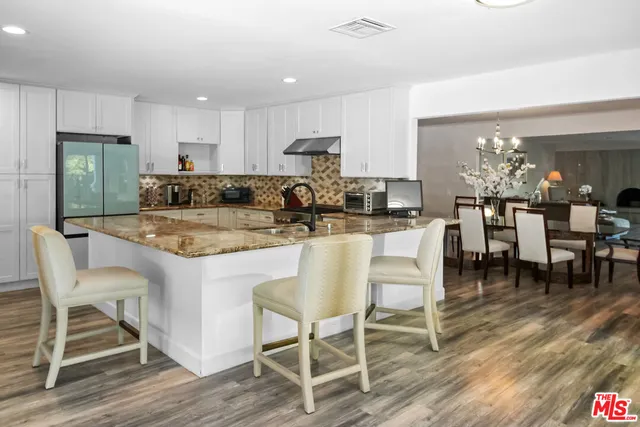 a dining table with chairs and kitchen view