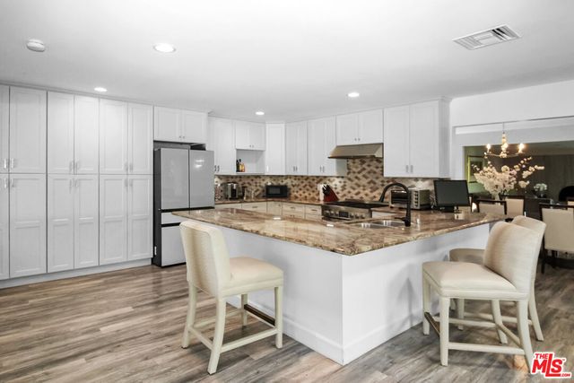 a kitchen with stainless steel appliances granite countertop a table chairs stove a refrigerator and cabinets