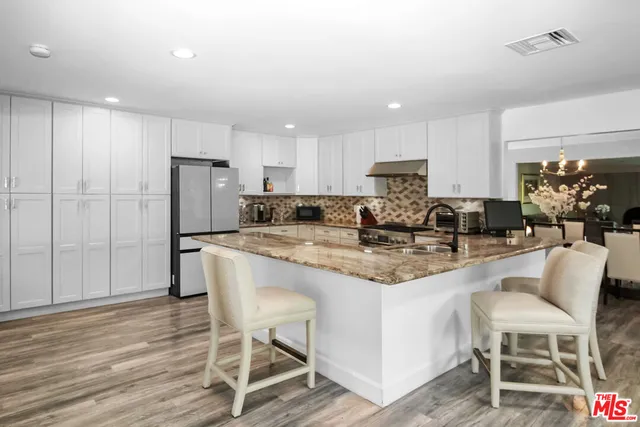 a kitchen with stainless steel appliances granite countertop a table chairs stove a refrigerator and cabinets