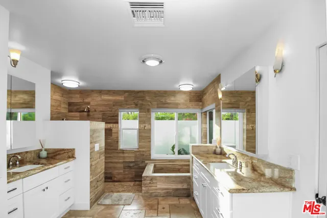 a spacious bathroom with a granite countertop tub a sink and a large mirror