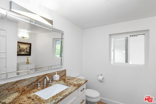 a bathroom with a granite countertop sink and a shower
