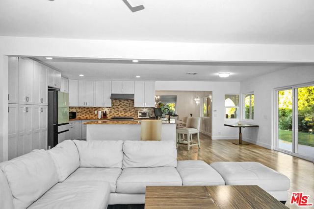 a living room with furniture white walls and view of kitchen