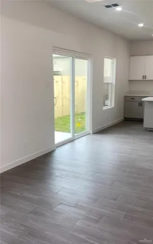 a view of an empty room with a window and wooden floor