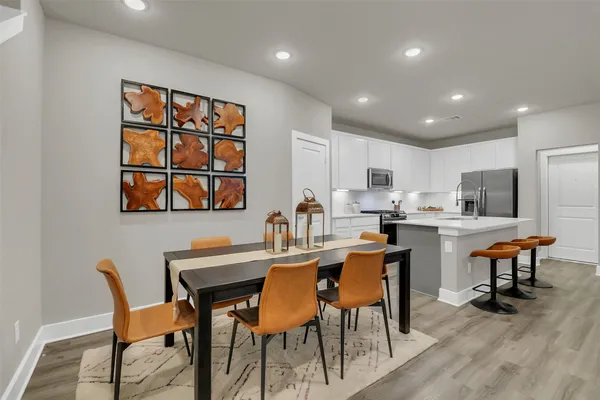 a dining room with stainless steel appliances kitchen island granite countertop a dining table chairs and a refrigerator