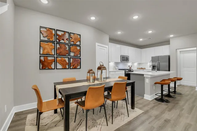 a dining room with stainless steel appliances kitchen island granite countertop a dining table chairs and a refrigerator