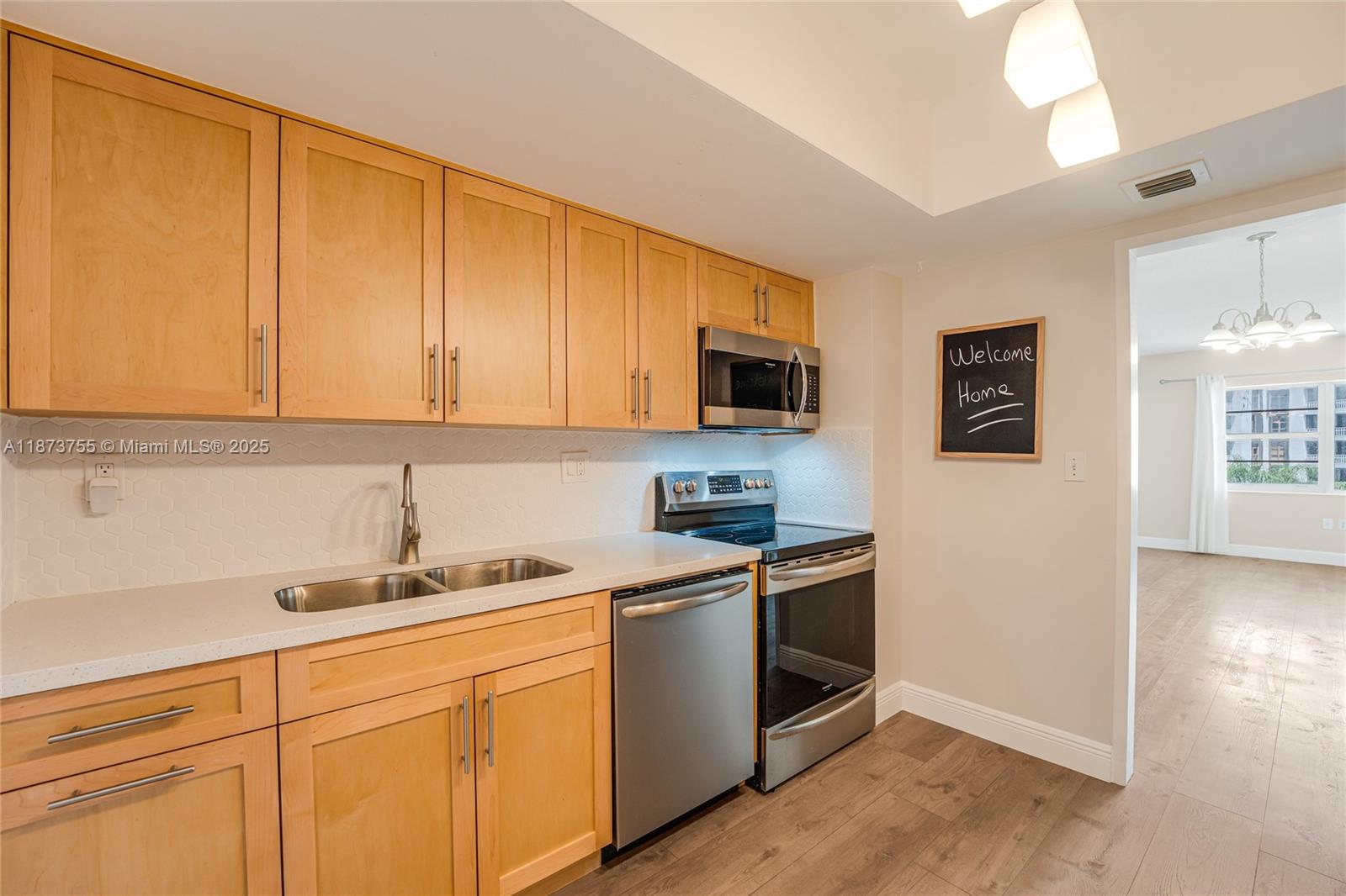 1700 Northeast 105th Street, Unit 505 Miami Shores, FL 33138 - Photo 6 of 20 a kitchen with stainless steel appliances granite countertop a sink a stove a microwave and cabinets