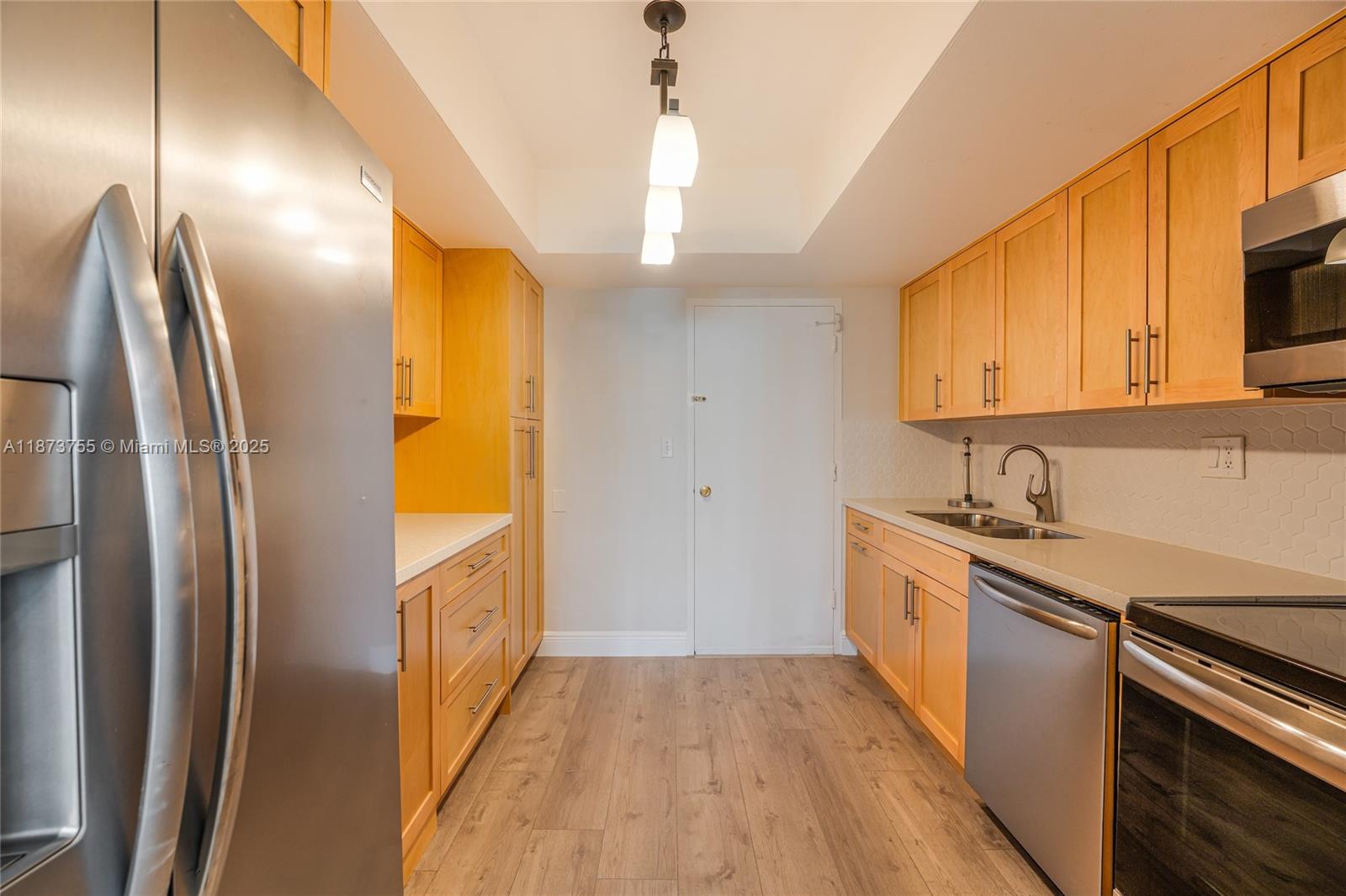 1700 Northeast 105th Street, Unit 505 Miami Shores, FL 33138 - Photo 8 of 20 a kitchen with stainless steel appliances granite countertop a refrigerator a sink dishwasher a stove and white countertops with wooden floor
