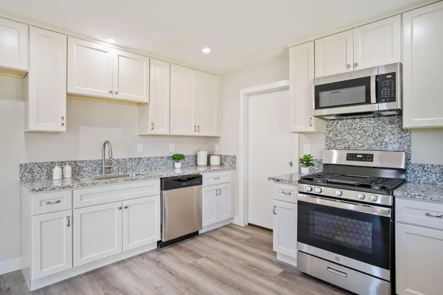 a kitchen with granite countertop a stove top oven microwave and cabinets