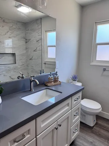 a bathroom with a granite countertop toilet a sink and a mirror