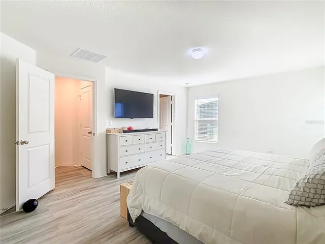 a bedroom with a bed and a flat tv screen on dresser