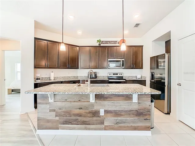 a kitchen with kitchen island granite countertop wooden cabinets and stainless steel appliances